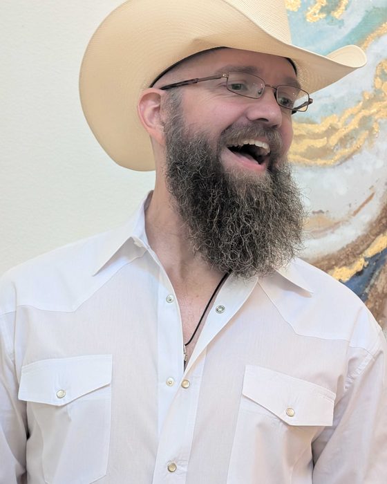 Van Santos, smiling, in a white western shirt and straw cowboy hat